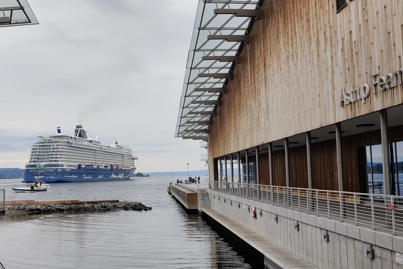 A cruise ship on the fjord, seen between the museum buildings on a late-summer evening