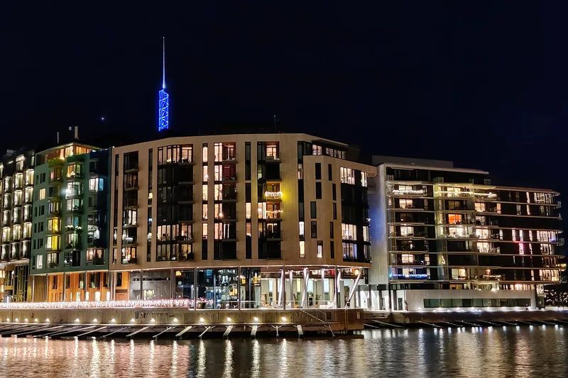 Tjuvholmen on a November evening, with lit windows reflected in the water and Tjuvtitten in blue