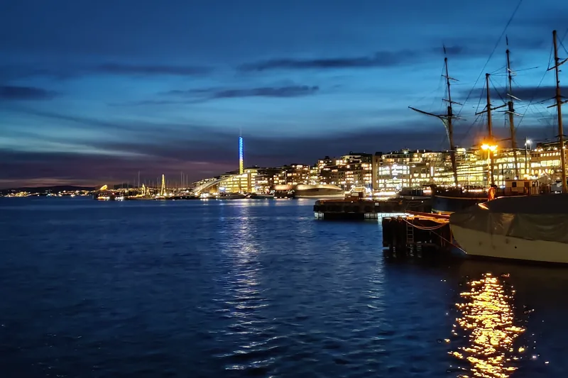 Tall ships at the quay at blue hour, with Tjuvholmen and Tjuvtitten in the background