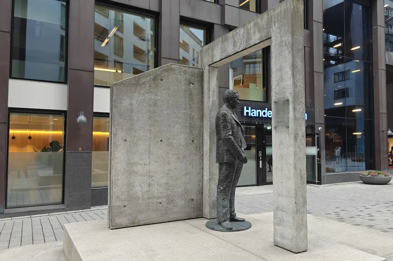 The statue of Olav Selvaag in front of the concrete portal
