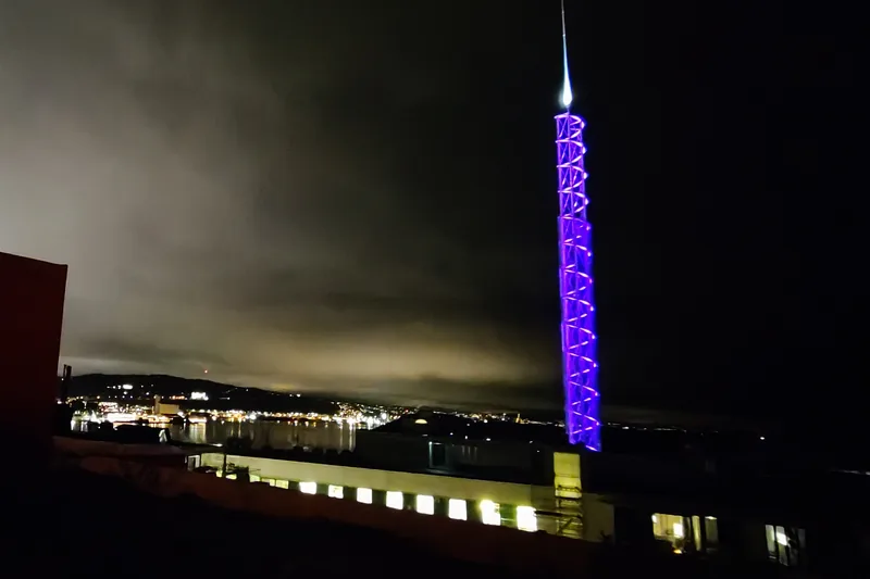 Tjuvtitten lit purple on an overcast November evening, with the city lights behind